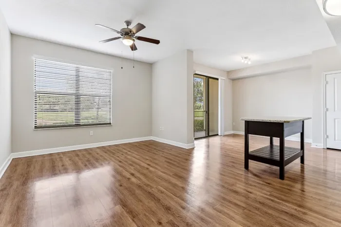 Spacious open-concept living area with view of kitchen and dining room, wood-style flooring, ceiling fan, and ample natural light at Lantower Westshore.