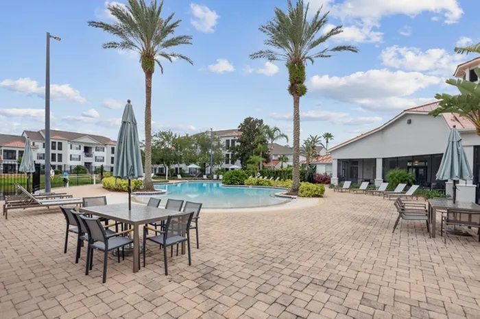 Zero-entry resort-style pool with sun deck, plenty of seating, and lush green shrubbery at Lantower Tortuga Bay.
