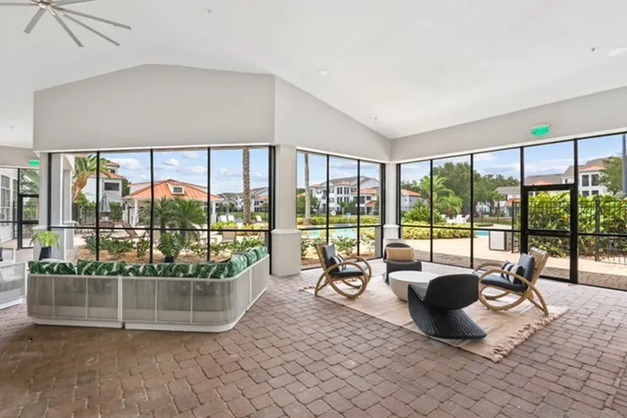 Lantower Tortuga Bay sun room with plenty of seating, large floor to ceiling windows with beautiful scenic views, brick floors, and fan.