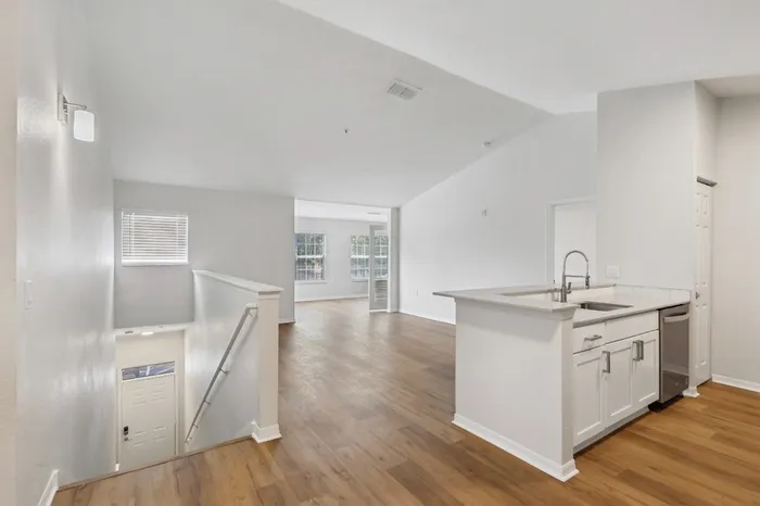 Spacious apartment at Lantower Tortuga Bay with open-concept kitchen and living room featuring ample natural light, wood plank flooring, den space, and vaulted ceilings.