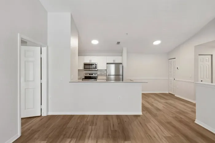 Apartment with open-concept kitchen and dining room featuring ample natural light, wood plank flooring, recessed kitchen lighting, and vaulted ceilings at Lantower Tortuga Bay.