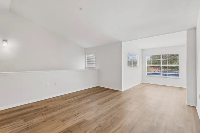Spacious apartment living room with natural light, wood plank floors, and vaulted ceilings at Lantower Tortuga Bay.