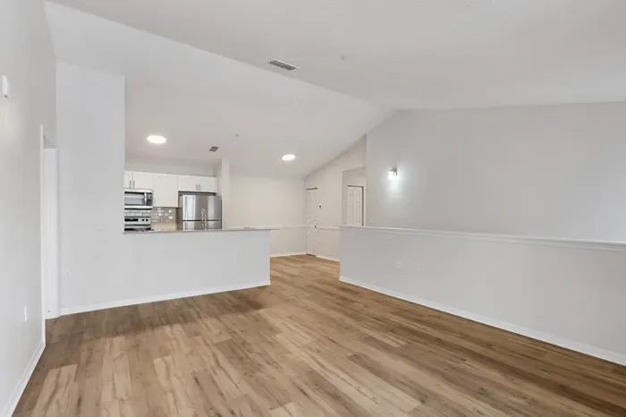 Spacious living room with view of kitchen and dining room, wood plant floors, recessed lighting, and vaulted ceilings at Lantower Tortuga Bay.