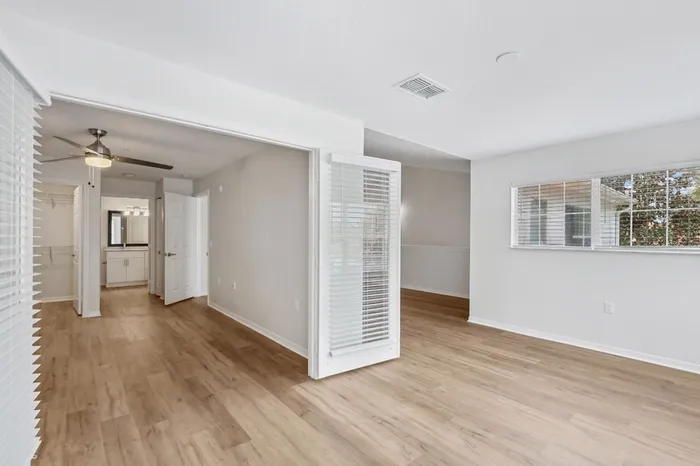 Spacious den with natural light opening and wood plant floors up to bedroom with ceiling fan, walk in closet, and bathroom at Lantower Tortuga Bay.
