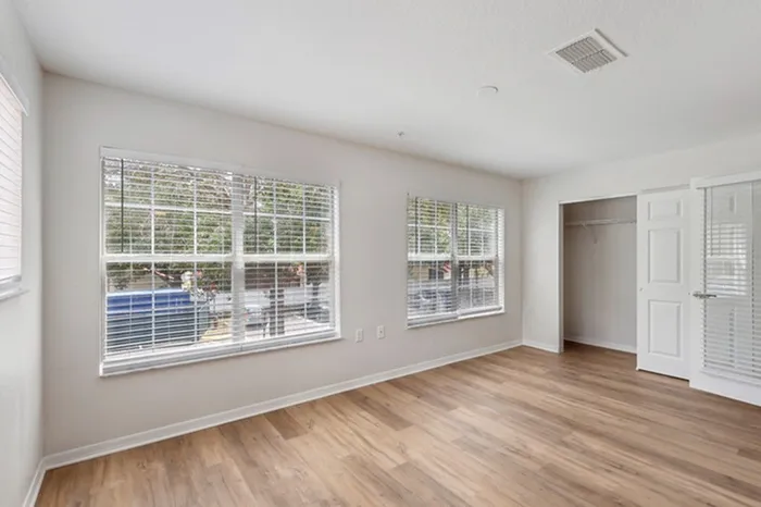 Large bedroom with ample natural light provided by 3 large windows, wood plank floors, and closet at Lantower Tortuga Bay.