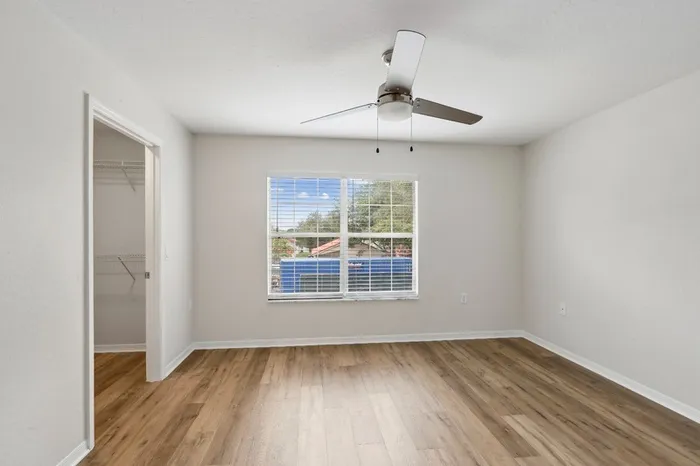Large bedroom with ceiling fan, wood plank floors, walk-in closet, and plenty of natural light provided by a large window at Lantower Tortuga Bay.