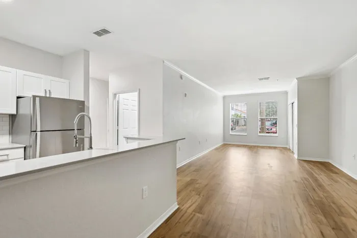 Spacious open-concept living and kitchen area with wood plant flooring and natural light provided by two windows at Lantower Tortuga Bay.