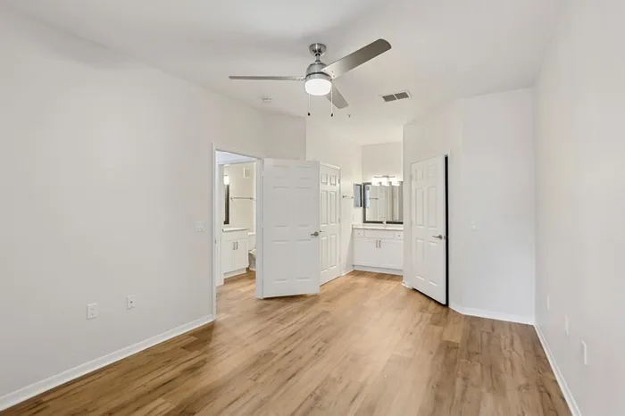 Spacious bedroom with wood plant floors, ceiling fan, walk in closet, and vanity at Lantower Tortuga Bay.