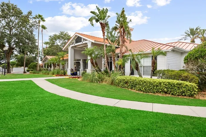 Lush landscaping with palm trees, green grass, and tropical foliage at Tortuga Bay Apartments in Orlando, FL.