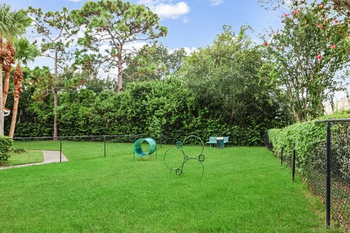 Lantower Tortuga Bay dog park with lush green grass, trees, and agility play equipment.