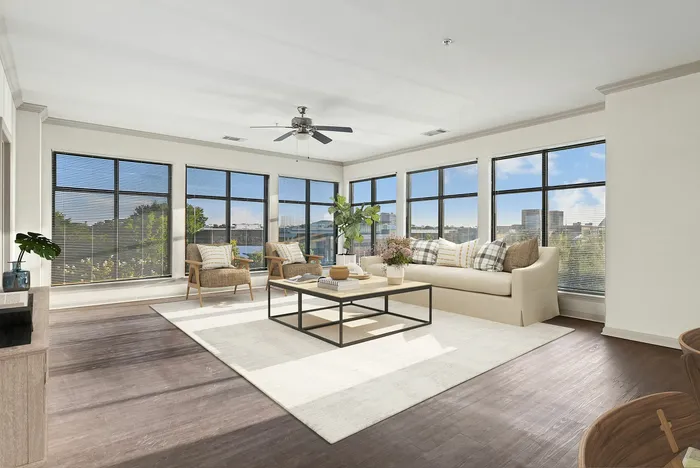 Spacious wood floored living room with access to private patio, has ample room for furniture, has a ceiling fan, and a modern finish at Lantower The Cortona