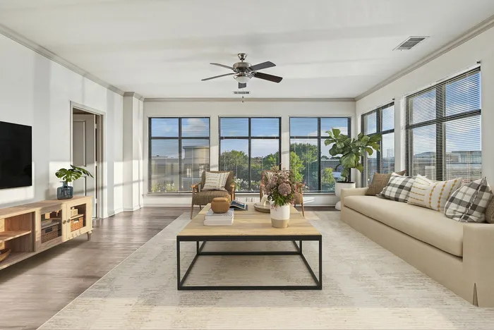 Spacious wood floored living room with access to private patio, has ample room for furniture, has a ceiling fan, and a modern finish at Lantower The Cortona