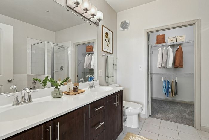 Large bathroom with a large, well lit mirror, white countertops, tiled shower and bathtub, and wood-style plank flooring at Lantower The Cortona