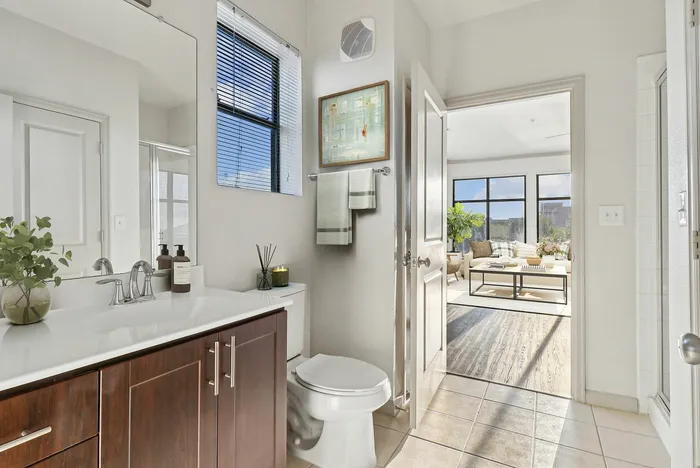 Large bathroom with a large, well lit mirror, white countertops, tiled shower and bathtub, and wood-style plank flooring at Lantower The Cortona
