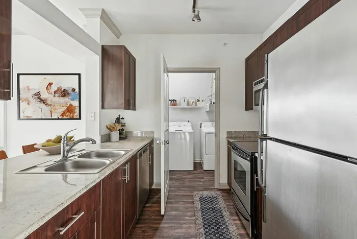 Modern kitchen with glossy countertops, stainless steel appliances, and wood cabinets at Lantower The Cortona