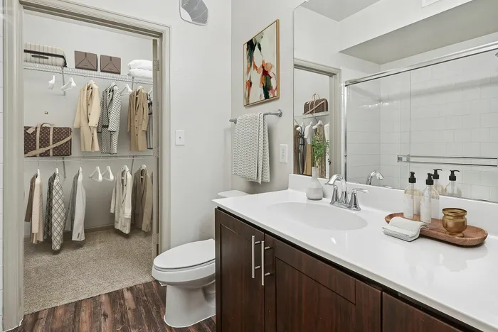Large bathroom with a large, well lit mirror, white countertops, tiled shower and bathtub, and wood-style plank flooring at Lantower The Cortona