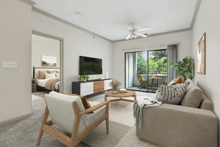 Spacious carpet floored living room with access to private patio, has ample room for furniture, has a ceiling fan, and a modern finish at Lantower The Cortona