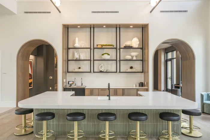 Elegant modern kitchen with a large island, stylish bar stools, and chic shelving display in a contemporary apartment.