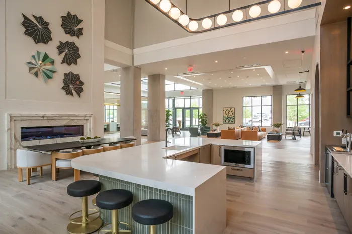 Luxurious open-concept living space with modern kitchen, stylish bar seating, elegant lounge area, and eye-catching wall art.
