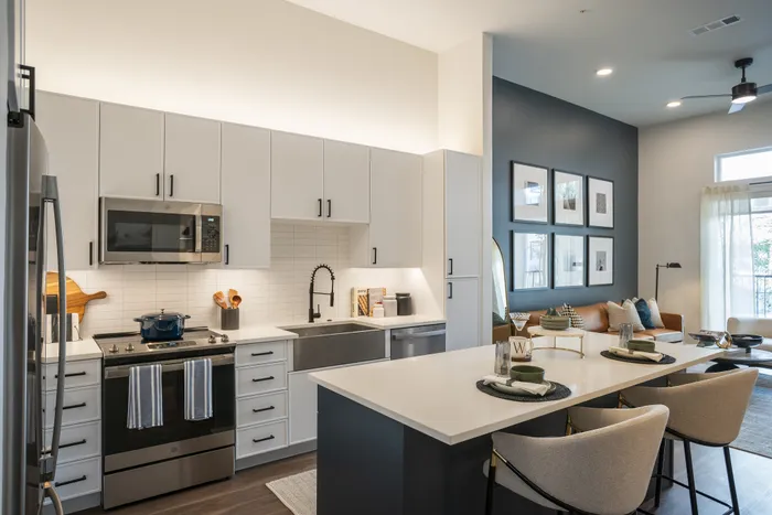 Chic open-plan kitchen with sleek white cabinetry, modern appliances, and a cozy living room with stylish decor and ample natural light.