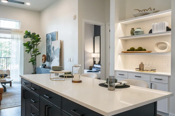 Bright and elegant apartment interior featuring an open-concept kitchen island with sleek countertops, stylish shelving, and modern decor.