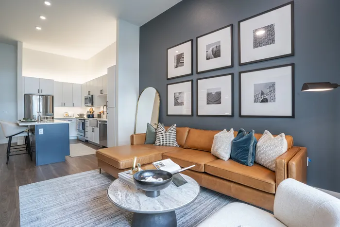 Contemporary living space with a chic open-concept kitchen, stylish leather sofa, and elegant wall art for a cozy urban vibe.