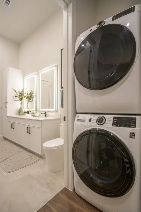 Chic bathroom with modern dual sinks, elegant lighting, and in-unit stacked washer and dryer.