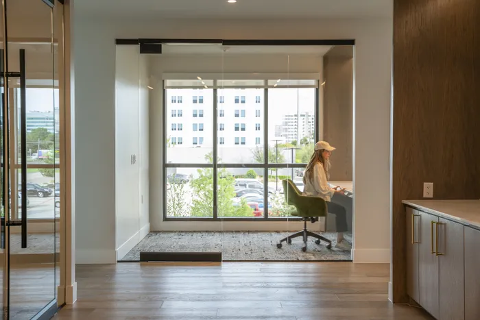 Modern apartment interior with elegant wood flooring, an inviting workspace featuring a large window, and a comfortable seating area offering natural light and serene views.