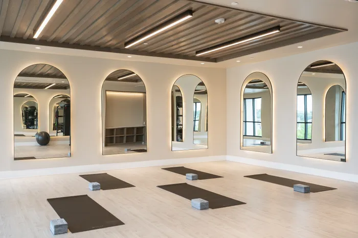 Luxurious yoga studio with elegant mirrors, sleek wooden ceiling, and neatly arranged mats creating a serene ambiance for wellness.