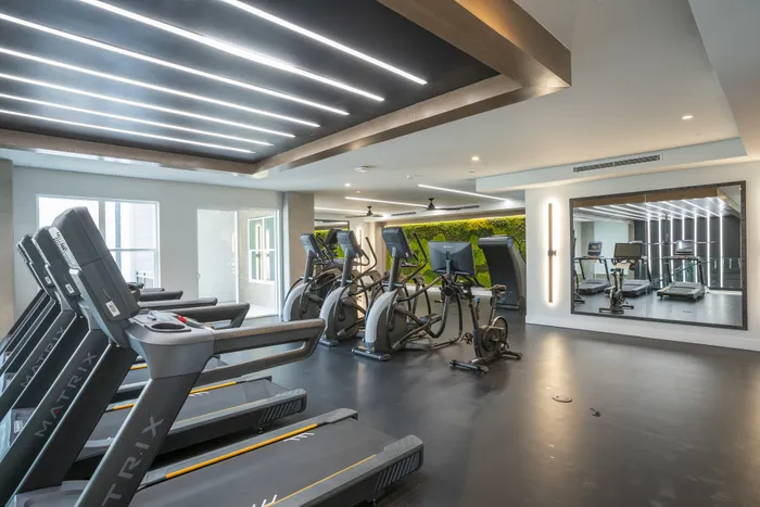 Modern fitness center featuring state-of-the-art treadmills, elliptical machines, and a vibrant green wall for a refreshing workout experience.