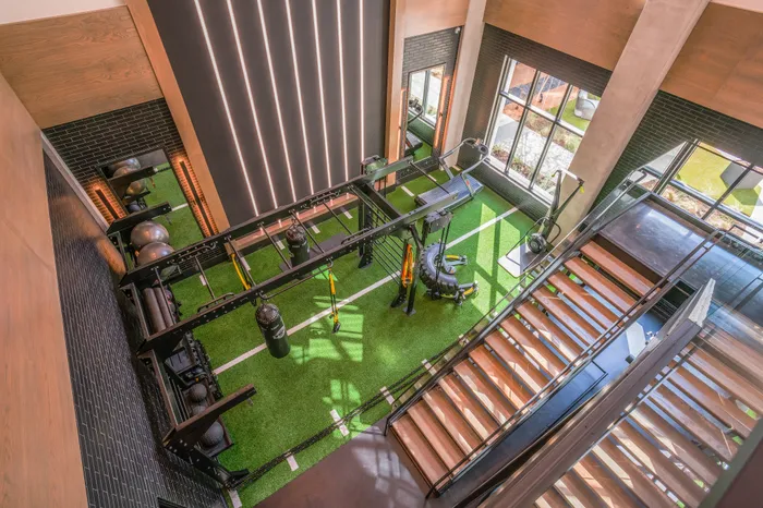 Modern fitness center with state-of-the-art equipment, vibrant green indoor turf, and ample natural light, perfect for energizing workouts.