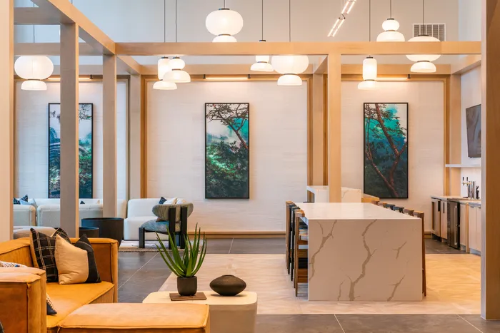 Modern luxury apartment lounge featuring elegant pendant lighting, a stylish marble island, and contemporary artwork.