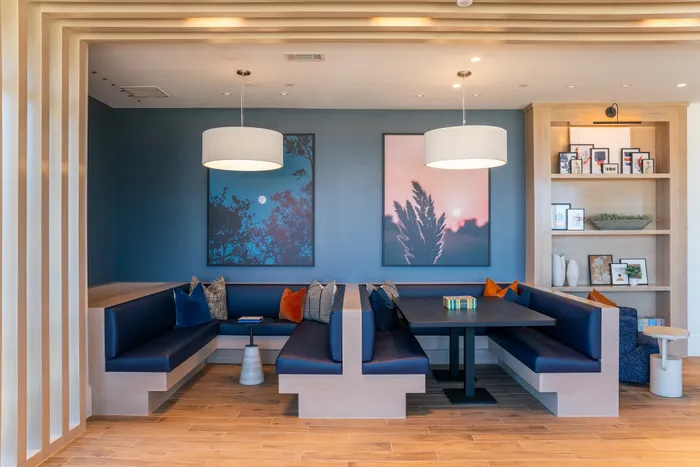 Modern dining area with navy blue banquette seating, elegant lighting, and artistic wall decor, creating a cozy and stylish ambiance.