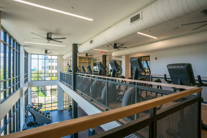 Modern fitness center with panoramic windows, high ceilings, and a range of high-end cardio machines.