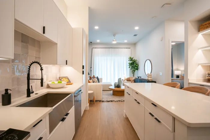 Bright and modern open-concept kitchen with sleek cabinetry, leading into a cozy living area adorned with contemporary decor.