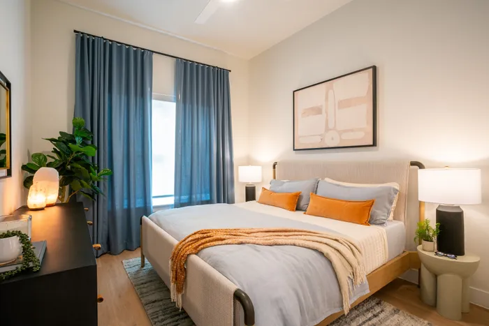 Chic bedroom featuring elegant decor with soft lighting, a cozy bed adorned with cushions, and modern artwork, creating a serene oasis.