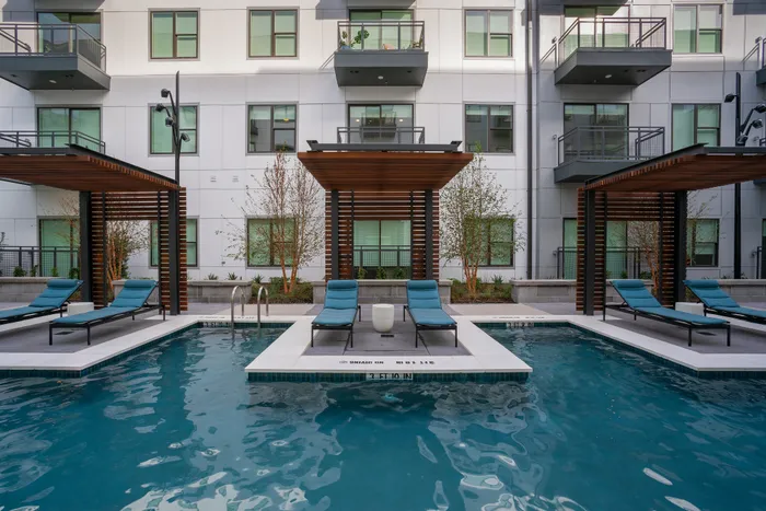Luxury apartment complex with inviting pool area featuring stylish cabanas and comfortable lounge chairs, perfect for relaxation and leisure.