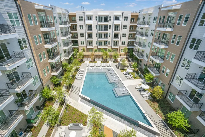 Modern apartment complex with a stunning central pool, lush landscaping, and contemporary architecture.