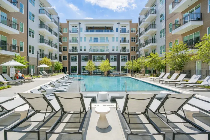 Luxurious apartment complex with a sparkling pool, surrounded by modern architecture and lush greenery, offering a resort-style ambiance.