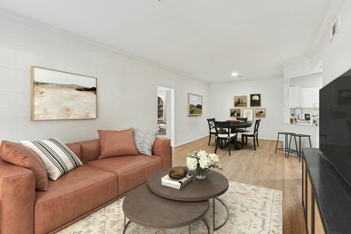 Elegant living room with a cozy brown leather sofa, nested coffee tables, and chic dining area leading to a modern kitchen.