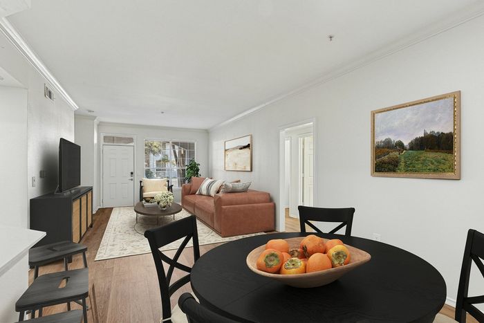 Contemporary living room with a cozy brown sofa, elegant decor, and a vibrant bowl of fruit on a sleek dining table.