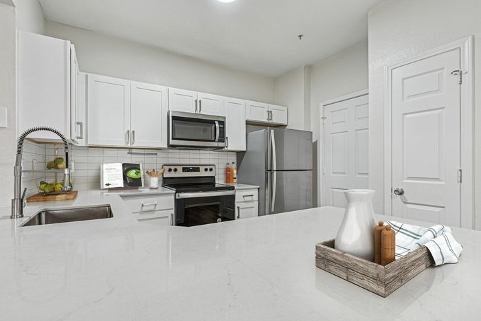 Modern kitchen with sleek white cabinets, stainless steel appliances, and elegant marble countertops, perfect for culinary enthusiasts.