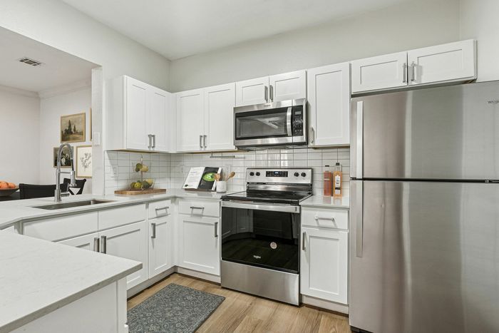 Chic modern kitchen showcasing sleek stainless steel appliances, elegant white cabinetry, and stylish tiled backsplash, perfect for culinary enthusiasts.