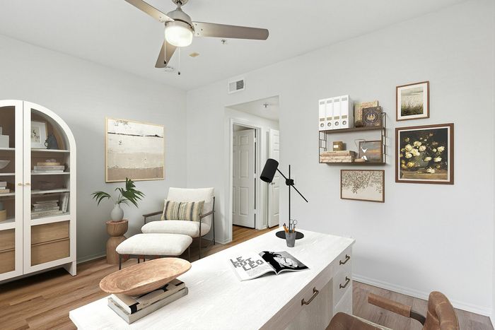 Chic home office design with a modern desk, comfortable chair, and stylish decor accented by wall art and a ceiling fan.