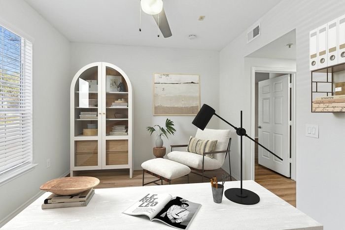Bright and airy study room featuring a modern armchair, sleek desk lamp, and elegant storage shelves with books and decor.