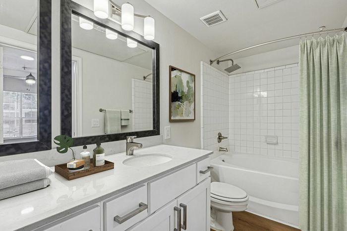 Elegant bathroom featuring a stylish vanity, modern fixtures, and a spacious bathtub with a serene green shower curtain.