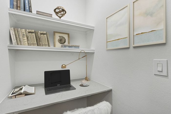 Cozy nook with elegant shelving, stylish décor, and a modern workspace equipped with a laptop and a chic lamp.