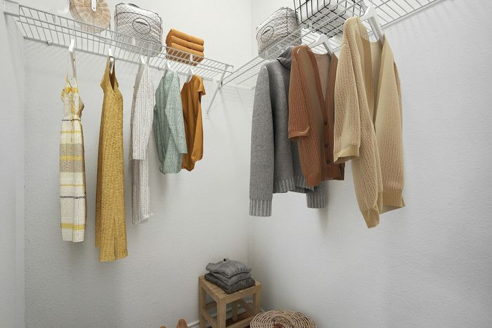 Spacious walk-in closet with neatly organized clothes, cozy sweaters, and stylish dresses, featuring ample shelving and storage space.