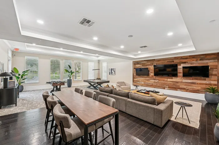 Luxurious entertainment lounge with sleek wooden accents, plush seating, and dual mounted televisions, offering a stylish and inviting space for relaxation.