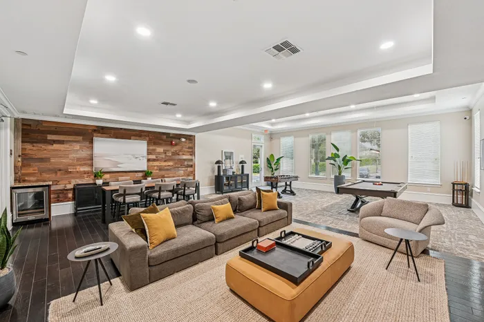 Spacious and modern lounge area featuring stylish seating, a pool table, and elegant wood accents, perfect for entertainment and relaxation.